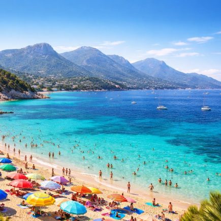 plage-mediterranee-parasols-montagnes-ciel